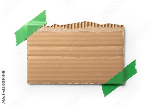 Piece of torn brown cardboard attached with green masking tape isolated on white background space