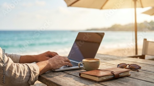Digital nomad working on laptop at beach cafe table with coffee and notebook, remote work lifestyle concept, male freelancer typing on computer outdoors