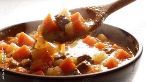A video of a delicious homemade stew being stirred with a wooden spoon in a pan