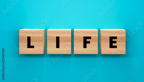 Bild auf Leinwand LIFE spelled out in wooden blocks: Four wooden cubes, each with a single black letter, spell out the word LIFE against a vibrant teal background, representing existence and vitality