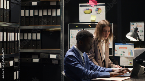 Obraz na plátne Determined private investigators discussing and doing extensive investigation to solve crime in room crammed with papers and evidence, Inspectors, both male and female, carefully examining clues