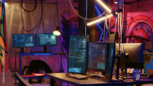 Canvas-taulu Programming language on PC screens in empty messy hackers base of operations with grunge graffiti drawings sprayed on walls, Neon lit ghetto hideout used by criminals to commit illegal activities