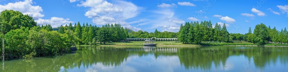 Obraz premium 晴天の日に水辺に広がる豊かな森と洋風回廊のパノラマ風景