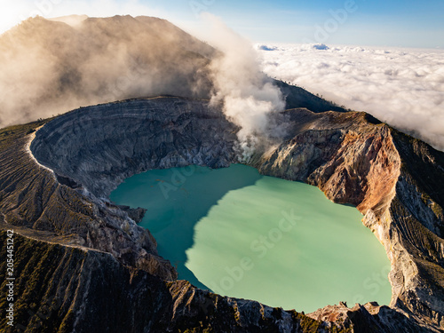 Aerial view of rock cliff at Kawah Ijen volcano with turquoise sulfur water lake at sunrise.Amazing nature landscape view at East Java, Indonesia. Natural landscape background