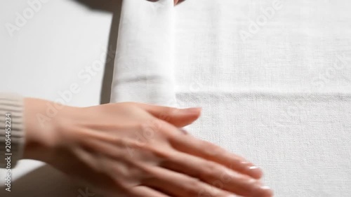 A person's hand gently touching a soft, white carpet in a serene indoor setting, captured in a calming video.