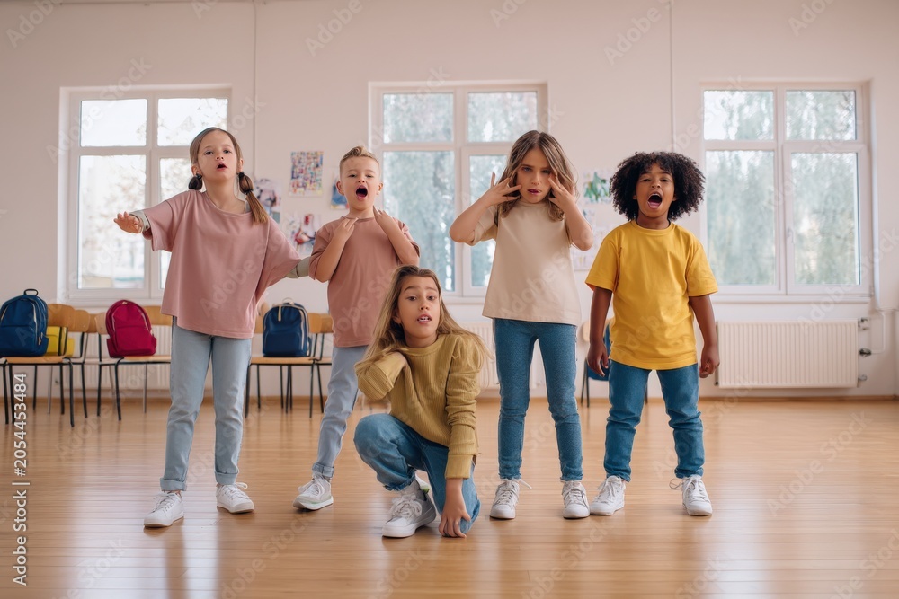 Fototapeta premium Diverse group of energetic children expressing excitement and surprise during a classroom activity