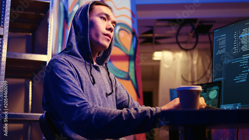 Obraz na płótnie Asian hacker in underground base getting past anti tamper measures implemented by companies trying to protect their products, Cracker trying to pirate software and video game releases, zoom in shot