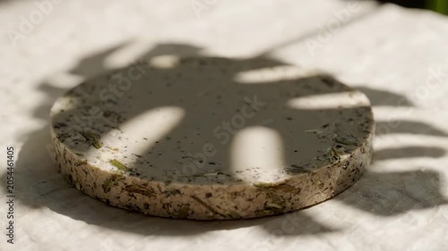 Bio based composite material round disc with natural texture and shadow on fabric and white surface in soft light