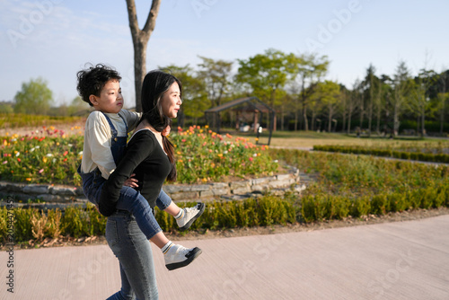Tableau sur toile Mom carries child through garden path