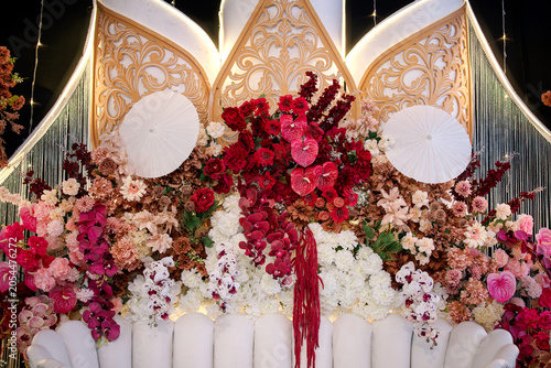 Close Up of Javanese Wedding Backdrop with Red Flowers and Paper Umbrellas