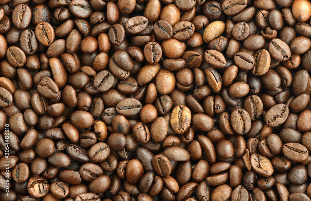 Fototapeta premium Detailed view on brown roasted coffee beans in big pile on table close up
