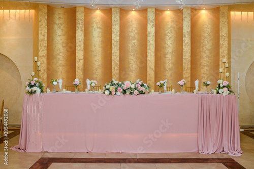 A table for the bride and groom in the ceremonial hall decorated with flowers and candles before the start of the celebration