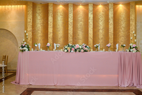 A table for the bride and groom in the ceremonial hall decorated with flowers and candles before the start of the celebration