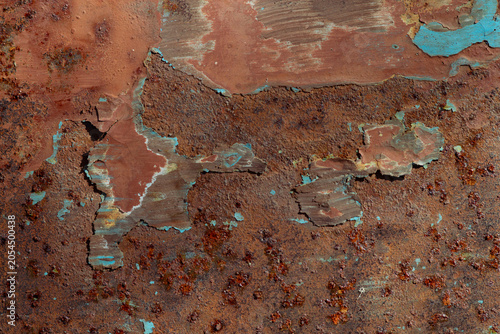 A rusty metal textured background. Peeling blue and green paint, a reddish-brown base. Raised patches of paint. The aged surface of the steel sheet.