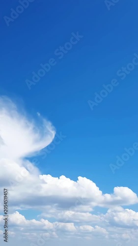Vertical view of fluffy white clouds in a bright blue sky on a clear sunny day