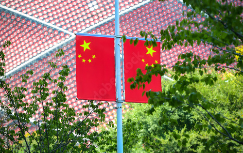 Bild auf Leinwand Chinese national flags on a city street with green trees