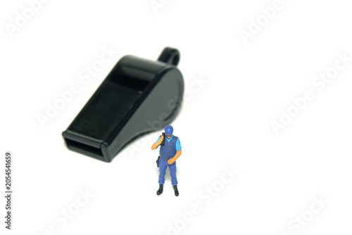 Miniature people toy figure photography. Justice collaborator and whistleblower protection concept. A security officer standing in front of black whistle. Isolated on white background