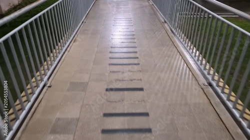 A slow forward camera movement perspective of an empty outdoor pedestrian overpass walkway with metal railings at night.