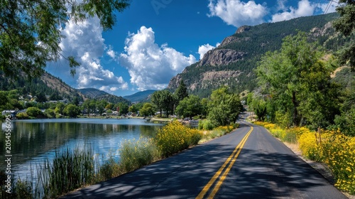 Winding road beside calm lake leads to small town nestled in mountain valley