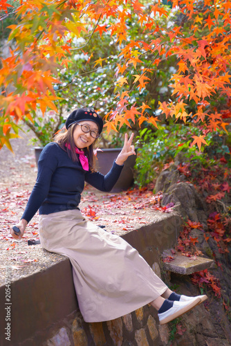 Happy Asian Female Tourist Enjoying Colorful Maple Leaves During Autumn Season in Mountain Park, Thailand