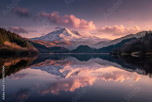 Majestic snow-capped mountain reflected perfectly in calm lake at sunset
