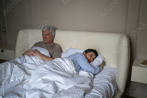 Obraz na plátně Exhausted elderly married lying in bed with frustration and disappointment after arguing, senior husband and wife holding out offence and disagreement, partners growing apart after crisis