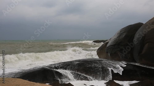 On a cloudy day, waves are crashing against huge rocks