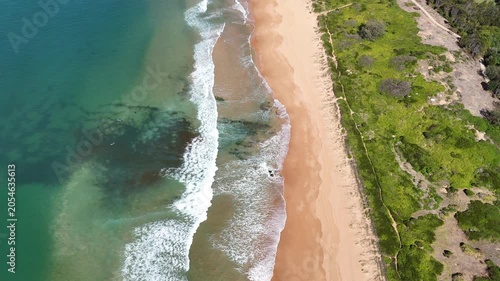 Drone video aerial view of waves crashing onto the shore on a beach in Sydney Australia in Summer 