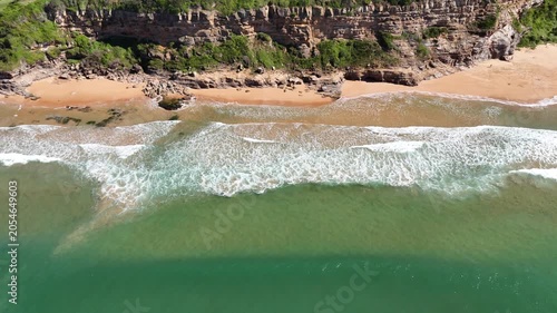 Drone video aerial view of waves crashing onto rocks near a beach in Sydney Australia
