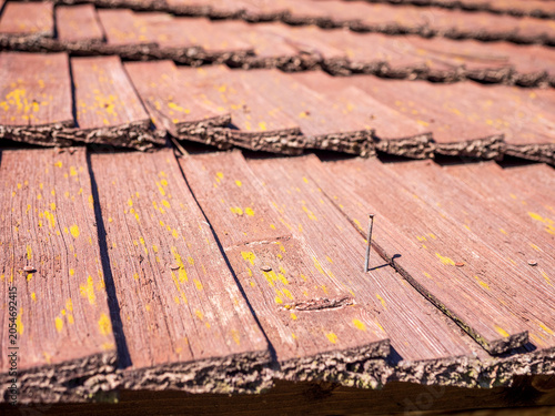 Fotografija Aged wooden shingle roof with exposed and loosening nails, close-up of weathered roofing material highlighting maintenance, repair and building inspection needs