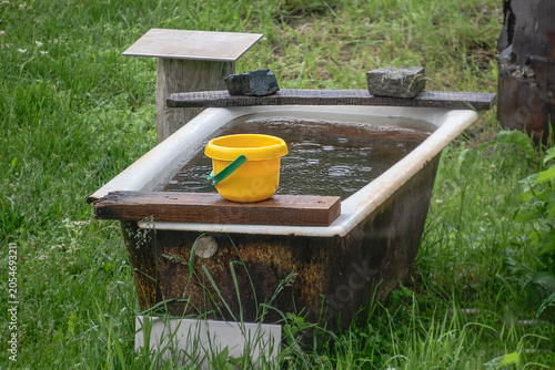 An old garden bathtub with water on a rainy summer day