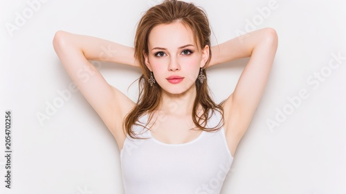 Young woman with arms raised behind her head against a light background