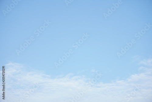 Expansive light blue sky with scattered soft white clouds, natural outdoor scene