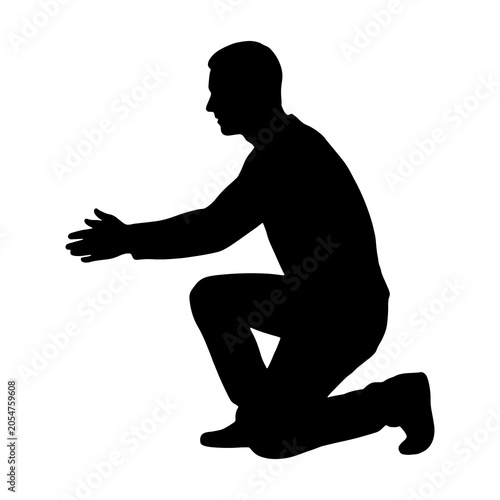 Fotografie Silhouette of a man kneeling and reaching forward with open hands