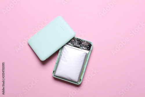 Fotografie Open broken power bank with a swollen battery on a pink background