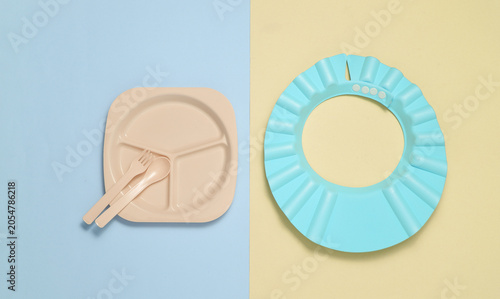 Set of plastic dishes for feeding baby on pastel background. Top view