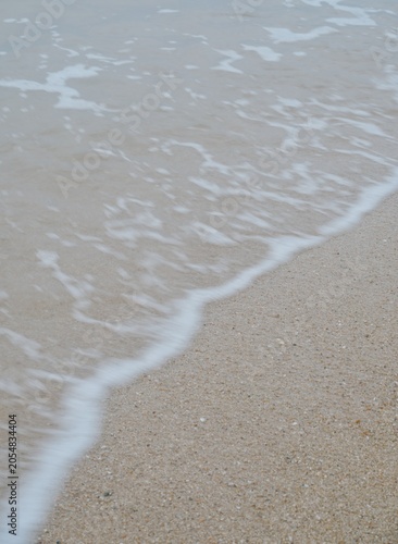 The waves are crashing against the sandy beach
