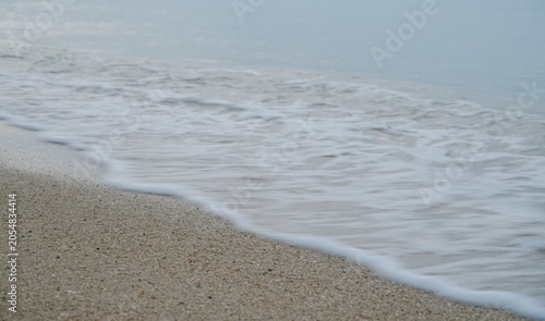 The waves are crashing against the sandy beach