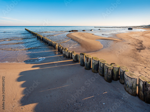 Buhnen am Strand der Ostsee im Morgenlicht unter blauem Himmel, Mecklenburg-Vorpommern, Deutschland