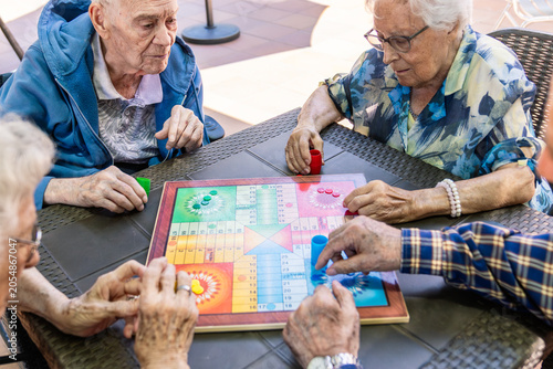 Obraz na plátně Senior adults enjoying a board game together at a nursing home, fostering social