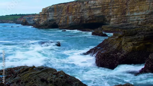 Crashing ocean waves against rugged cliffs and rocky shore, dynamic seascape with sea spray and deep blue water