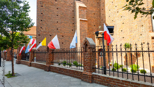 Quadro su tela Historic red brick church surrounded by an ornamental metal fence with brick pil