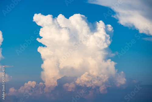 Photography Majestic Cumulonimbus Cloud Formation: A colossal cumulonimbus cloud dominates the sky, its towering white mass set against a brilliant blue backdrop, promising dramatic weather