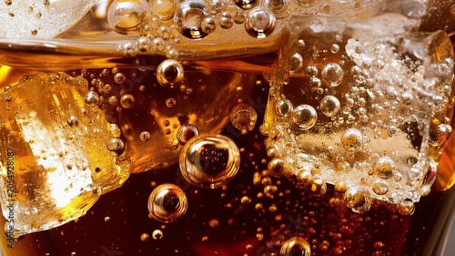 Refreshing cola drink with ice cubes and sparkling bubbles in close up beverage background