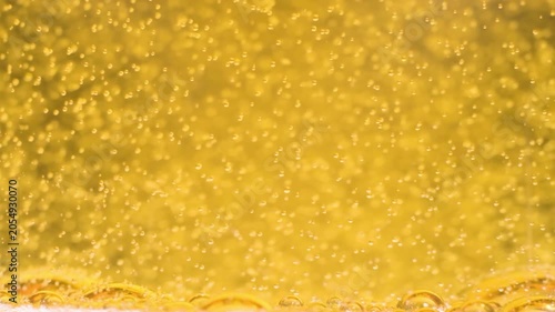 Macro close up of golden champagne bubbles rising in slow motion. Detailed carbonated drink, beer or sparkling wine abstract background