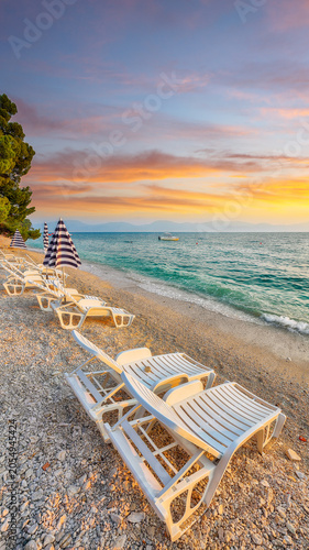 Amazing Sun loungers and beach umbrellas at sunset on the beach of Gradac in Makarska riviera.