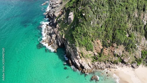 Cinematic Aerial Drone View at 45 Degrees Over Rocky Cliff and Turquoise Sea Coastline