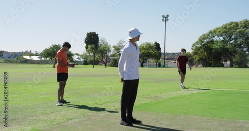 Indian bowler shifting and bowling ball at batsman taking guard at wicket, umpire watching