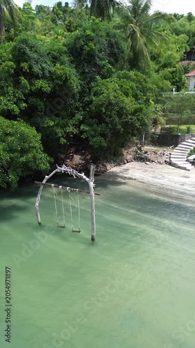 Aerial viwe of a swing set standing in shallow turquoise water at Weh Island Sabang, Indonesia. The Hawk Nest beach resort.
