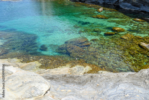 Rocky coast with crystal clear water in Chora on the island of Andros. Cyclades, Greece